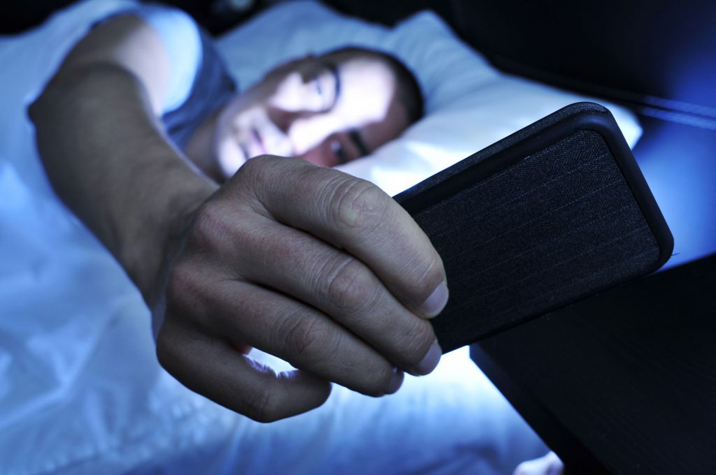 Closeup of a Young Man in Bed Looking at the Smartphone at Night Image