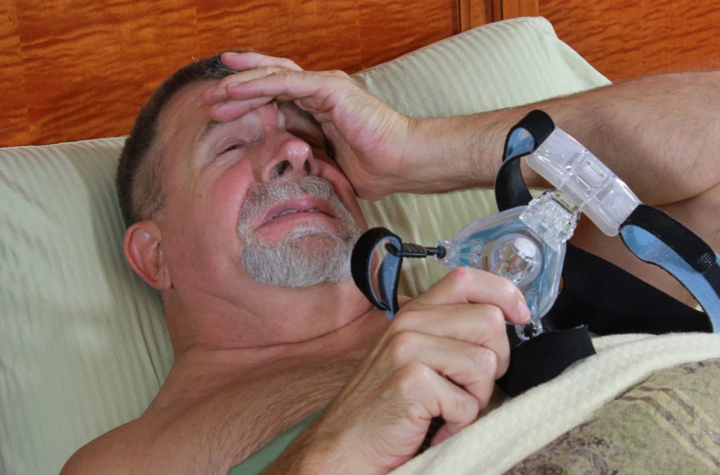 Adult Man Frustrated with CPAP Mask Image